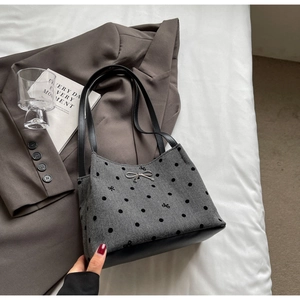 Detailed texture of grey herringbone fabric with black polka dots and silver bow buckle