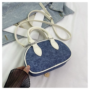 Dettaglio mini borsa in denim con finiture in pelle bianca e ciondolo a forma di orso