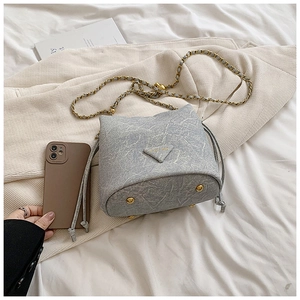 Detail of off-white marble pattern bucket bag with chain strap and protective base studs