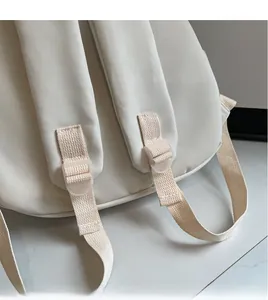 Detail of adjustable padded shoulder straps on a minimalist off-white canvas backpack
