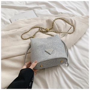 Detail of grey marble textured bucket bag with golden feet and chain strap