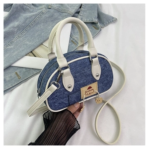 Dettaglio ravvicinato della mini borsa a cuscino in denim con manici bianchi e patch in pelle