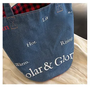 Dettaglio della borsa tote in denim con fodera a quadri e scritte tipografiche bianche