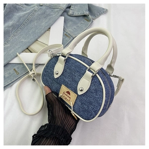 Dettaglio della borsa a cilindro in denim con manici bianchi e ricamo alla moda