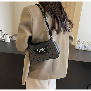 Detail der grauen Polka-Dot-Schultertasche mit silberner Schleife und gedrehtem Gurt