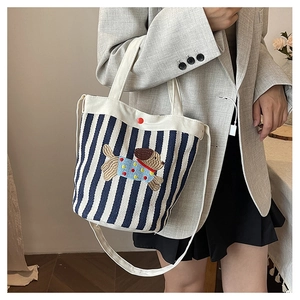Détail du sac seau en toile à rayures bleues et blanches avec broderie de chien brun