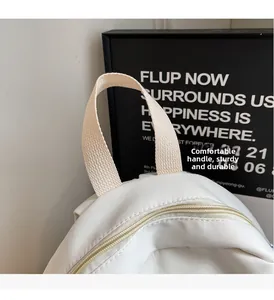 Detail of the woven handle and sturdy metal zipper on a white canvas backpack