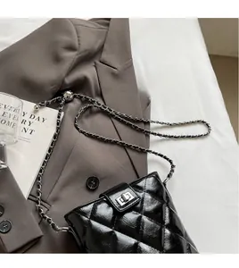 Detail of black quilted leather bucket bag with silver metal chain and twist lock clasp