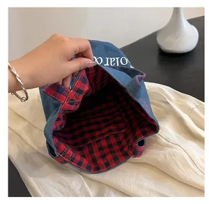Dettaglio della borsa a secchiello in denim con fodera a quadri rossi e interno ampio