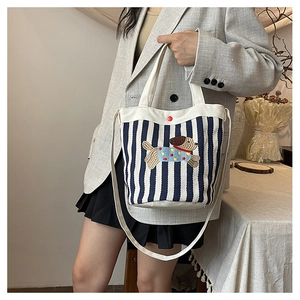 Détail du sac seau en toile rayée avec une broderie de chien de dessin animé