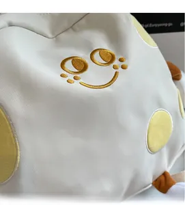 Detail of soft twill fabric with golden embroidered smile and plush texture on bag