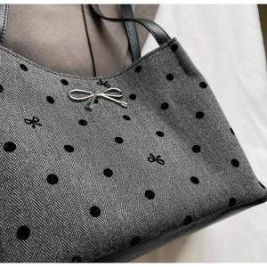 Detailed close-up of herringbone fabric with flocked dots and silver bow on handbag