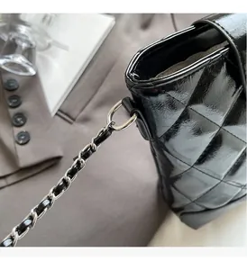 Close-up of black glossy quilted bucket bag with silver metal chain shoulder strap