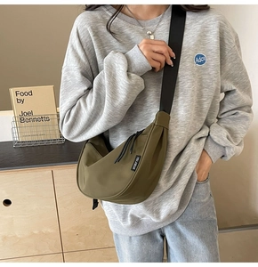 Olive green crescent nylon crossbody bag worn by a model with a black wide strap