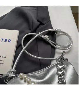 Details der silbernen Perlenhandtasche mit großem Perlengriff und Herz-Metallanhängern