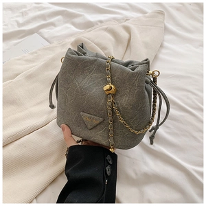 Detail of grey textured bucket bag with gold chain strap and chic triangle logo plaque