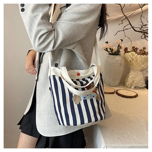 Détail du sac seau en toile rayée avec broderie ours mignonne et accent bouton rouge vif