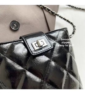 Detailed close-up of glossy quilted black chain bag with silver metallic twist lock