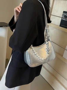 Silver hobo bag with pearl heart chain strap worn by a model in a black blazer