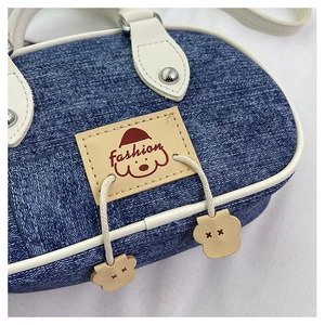 Dettaglio della mini borsa in denim con toppa in pelle a cucciolo e cuciture a contrasto