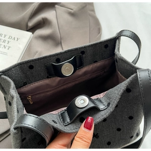 Detail of magnetic buckle closure and internal zipper pocket in a polka dot tote bag