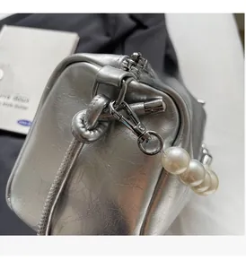 Detailansicht der silbernen Handtasche mit edlen Beschlägen und Perlen-Schultergurt