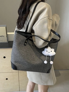 Minimalist grey canvas tote bag with black leather trim and white cloud charm accessory
