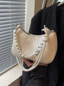 Chic cream underarm bag with pleated texture, pearl chain, and knotted shoulder strap