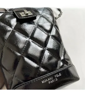Close-up of black quilted bucket bag featuring a metallic turn-lock and silver logo