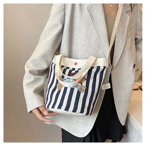 Détail d'un sac seau en toile rayé bleu et blanc avec écusson de chien sur un mannequin