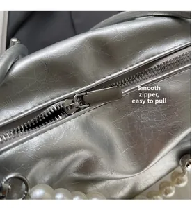 Detail der silbernen Metallic-Handtasche mit glattem Reißverschluss und Perlenhenkelkette