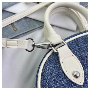 Dettaglio ravvicinato di patchwork in denim blu e pelle bianca con chiusura argento