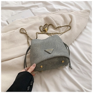 Detail of grey bucket bag showing stone texture, gold base studs and metal logo