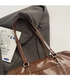 Detailed close-up of glossy brown leather tote with silver metal buckles and straps