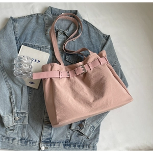 Chic pink fabric tote bag with belt buckle detail on a blue denim jacket background