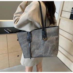 Close-up of the grey textured leather tote bag with embossed logo and sleek black handle
