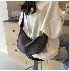 Detail of charcoal grey nylon half-moon crossbody bag with adjustable wide strap and logo tag