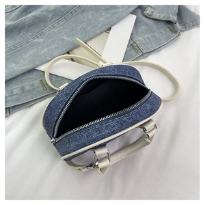Dettaglio mini borsa a bauletto in denim con apertura a zip e rifiniture in pelle bianca