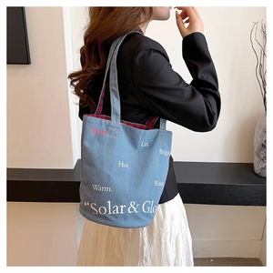Dettaglio della borsa a secchiello in denim blu con stampa Solar & Glo su una modella