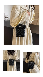 Detail of glossy quilted bucket bag with chain strap and silver twist-lock closure
