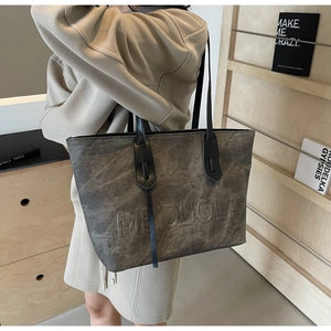 Detail of grey PU leather tote bag with embossed Meiduola text and thin black handles