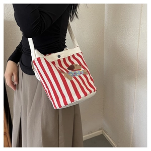 Sac seau en toile à rayures rouges avec broderie teckel porté à l'épaule sur modèle