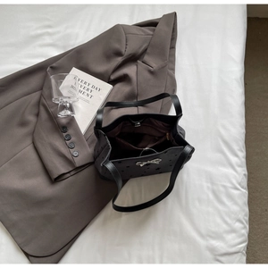 Close-up of star-perforated black tote bag with silver bow detail and internal zipper pocket