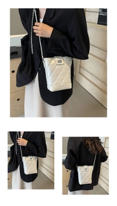Detailed close-up of quilted white bucket bag featuring silver chain and swivel lock