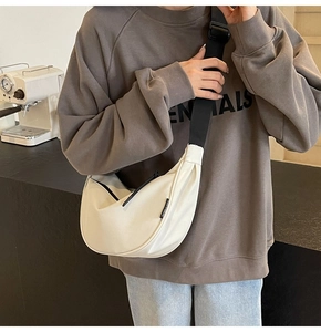 Detail view of large cream canvas dumpling bag with adjustable wide black strap