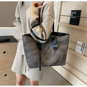 Detail of grey textured tote bag featuring embossed logo and spacious interior design