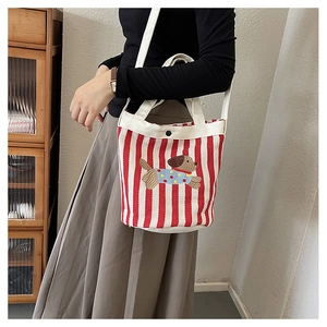 Détail du sac seau en toile à rayures rouges avec chiot brodé et fermeture magnétique