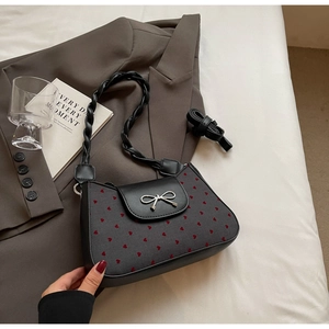 Details der grauen Herzdruck-Tasche mit silberner Schleife und gedrehtem Tragegriff