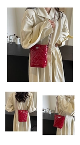 Close-up of red quilted patent leather bucket bag with silver chain and twist lock