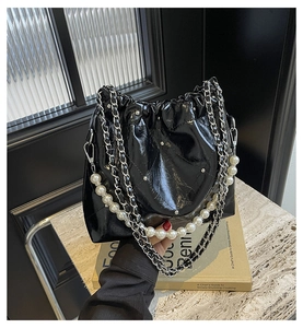 Detail of black quilted PU bucket bag with silver chain and elegant pearl handle